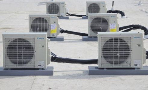 Multiple Daikin mini-split outdoor units installed on a commercial rooftop with insulated refrigerant lines.