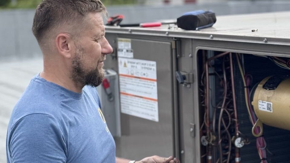 Levano Pro HVAC technician reviewing the data plate and components of an open rooftop unit