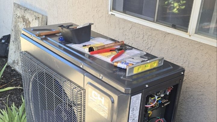 Heat pump outdoor unit with the service panel open and tools set out during a repair