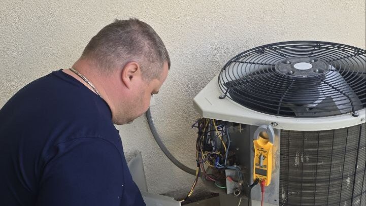 Levano Pro HVAC technician measuring current on an outdoor unit with a clamp meter