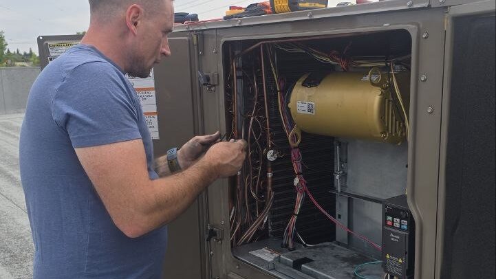 Levano Pro HVAC technician working on wiring inside an open outdoor HVAC unit