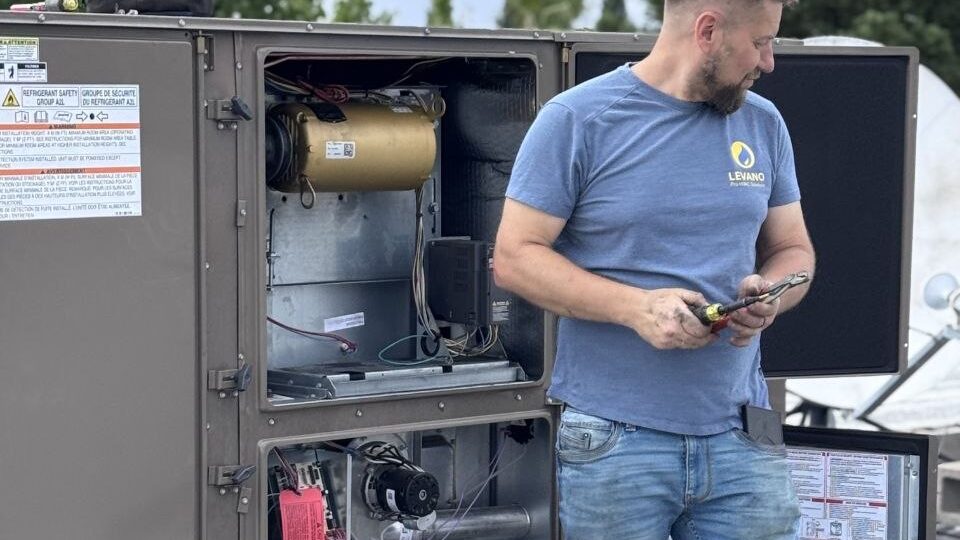 Levano Pro HVAC technician holding test tools beside an open HVAC unit
