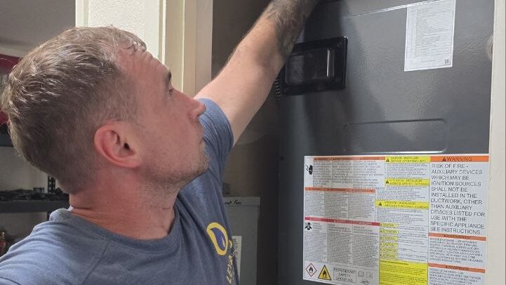 Levano Pro HVAC technician opening the service panel of an indoor furnace cabinet