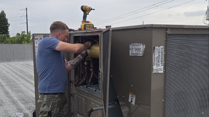 Levano Pro HVAC technician working inside a rooftop unit connected to supply and return ducts