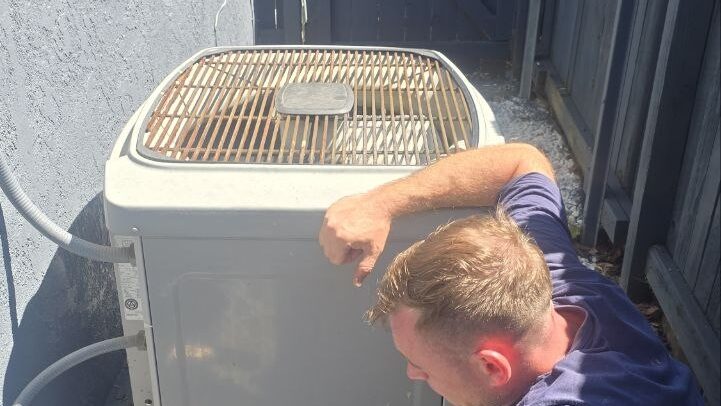 Levano Pro HVAC technician inspecting an aging condenser in a narrow Sacramento side yard