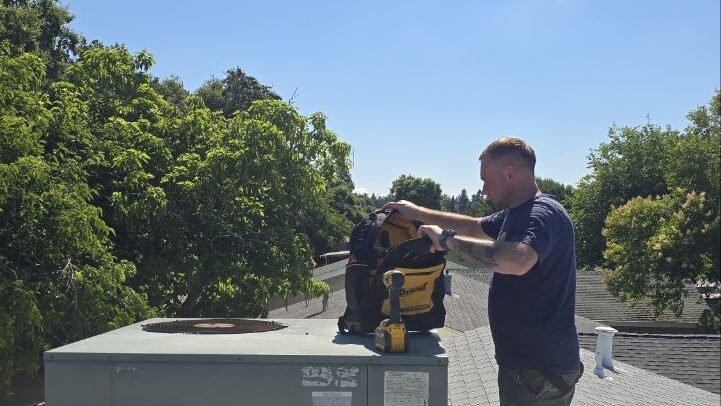 Levano Pro HVAC technician setting up tools on a rooftop package unit on a sunny day