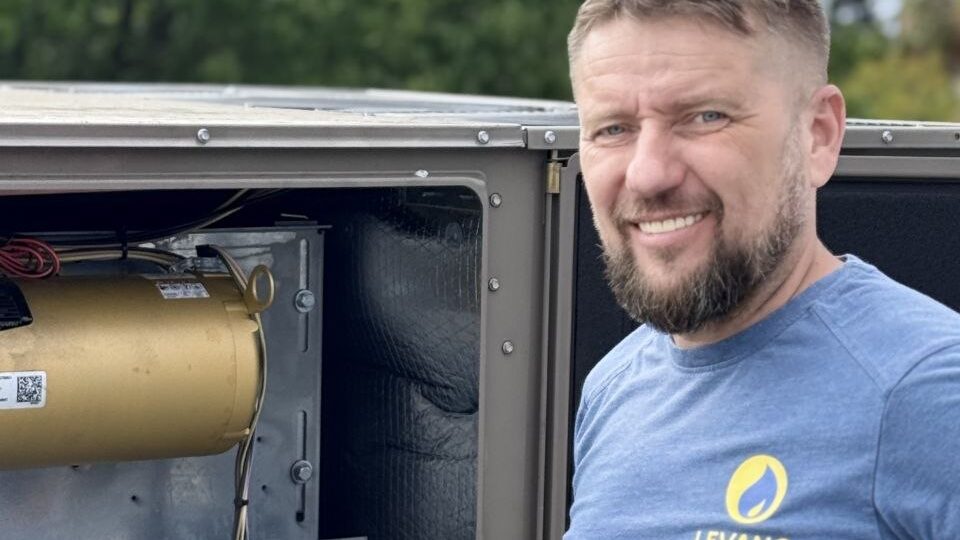 Levano Pro HVAC technician beside an open heat pump unit with its controls exposed