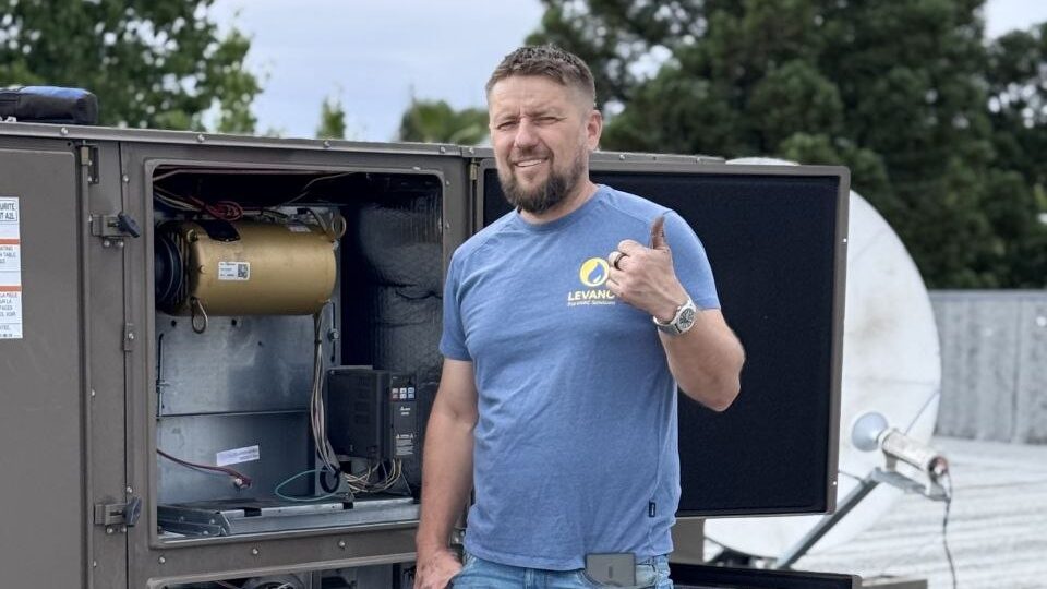 Levano Pro HVAC technician next to an open packaged gas heating and cooling unit