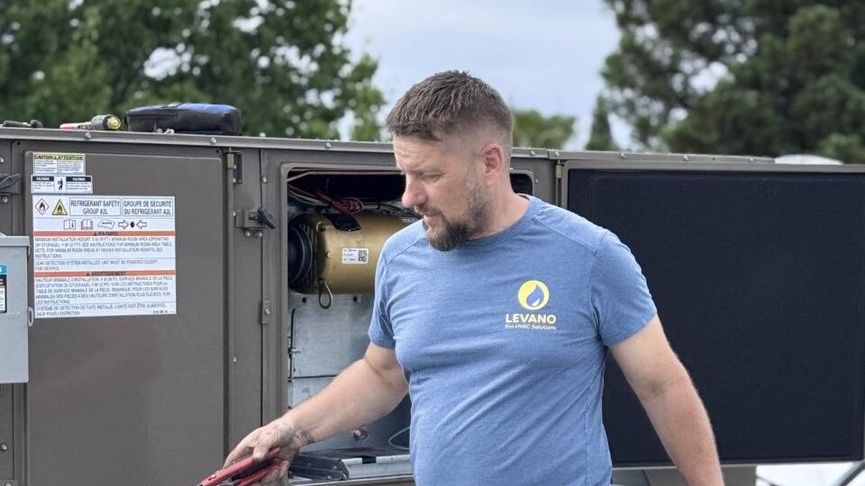 Levano Pro HVAC technician with tools beside an open rooftop heating and cooling unit